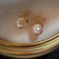 18K gold pearl stud earrings by MANDOTOS featuring elegant round pearls on simple gold posts.