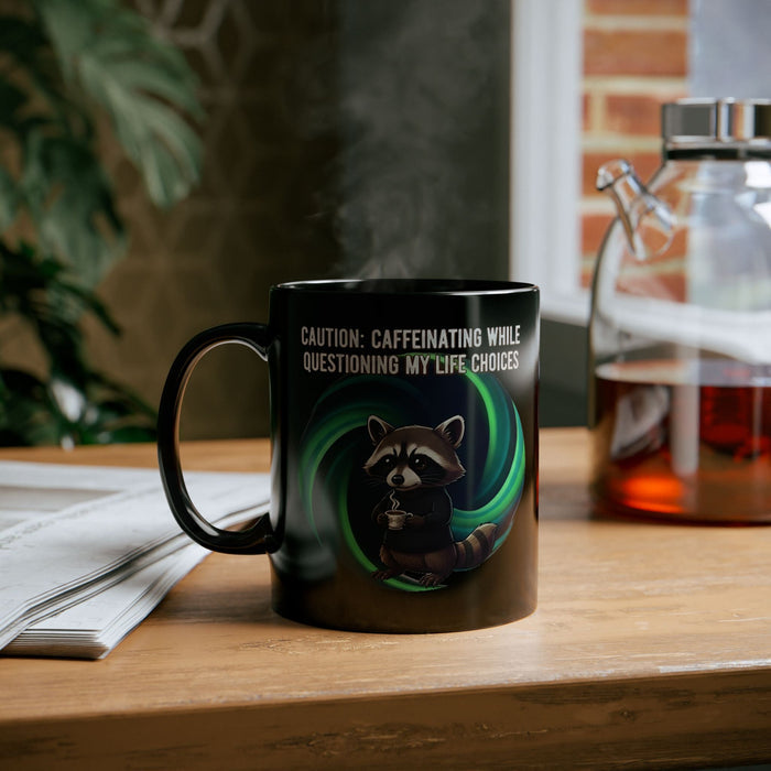 Black mug with a raccoon graphic and text on a wooden surface