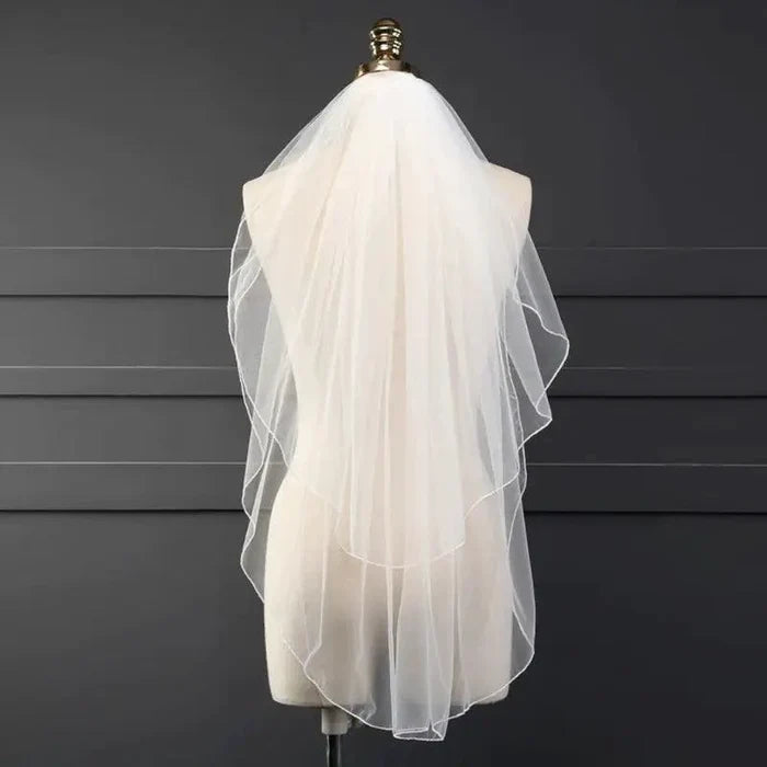 Ethereal double-tiered veil by MANDOTOS featuring delicate lace and soft tulle layers for a graceful bridal look.