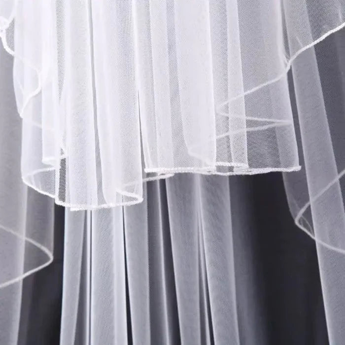 Ethereal double-tiered veil by MANDOTOS featuring delicate lace and flowing tulle for a romantic bridal look.