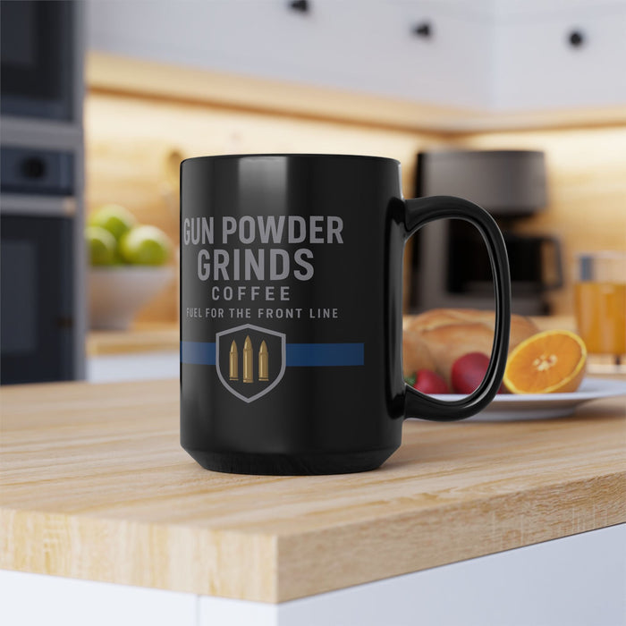 Black mug with 'Gun Powder Grinds Coffee' text on a kitchen counter.