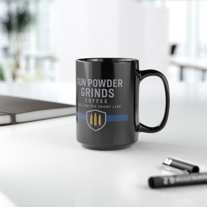 Black mug with 'Gun Powder Grinds Coffee' text on a white surface with blurred background