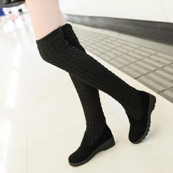Mandotos high flat over-the-knee stretch Martin boots displayed on a model, showcasing sleek black leather and pointed toe design.
