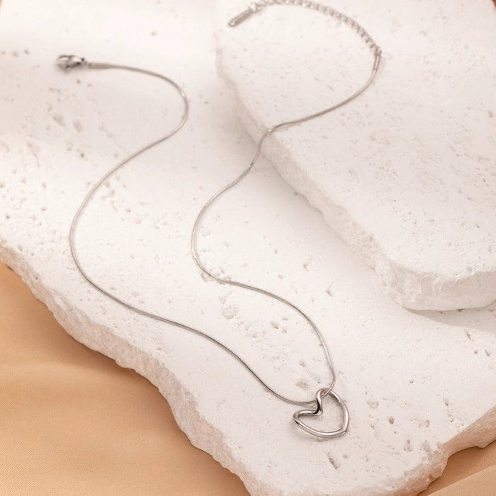 Stainless steel twist hollow heart necklace with clavicle chain by MANDOTOS, close-up view of the elegant jewelry piece.